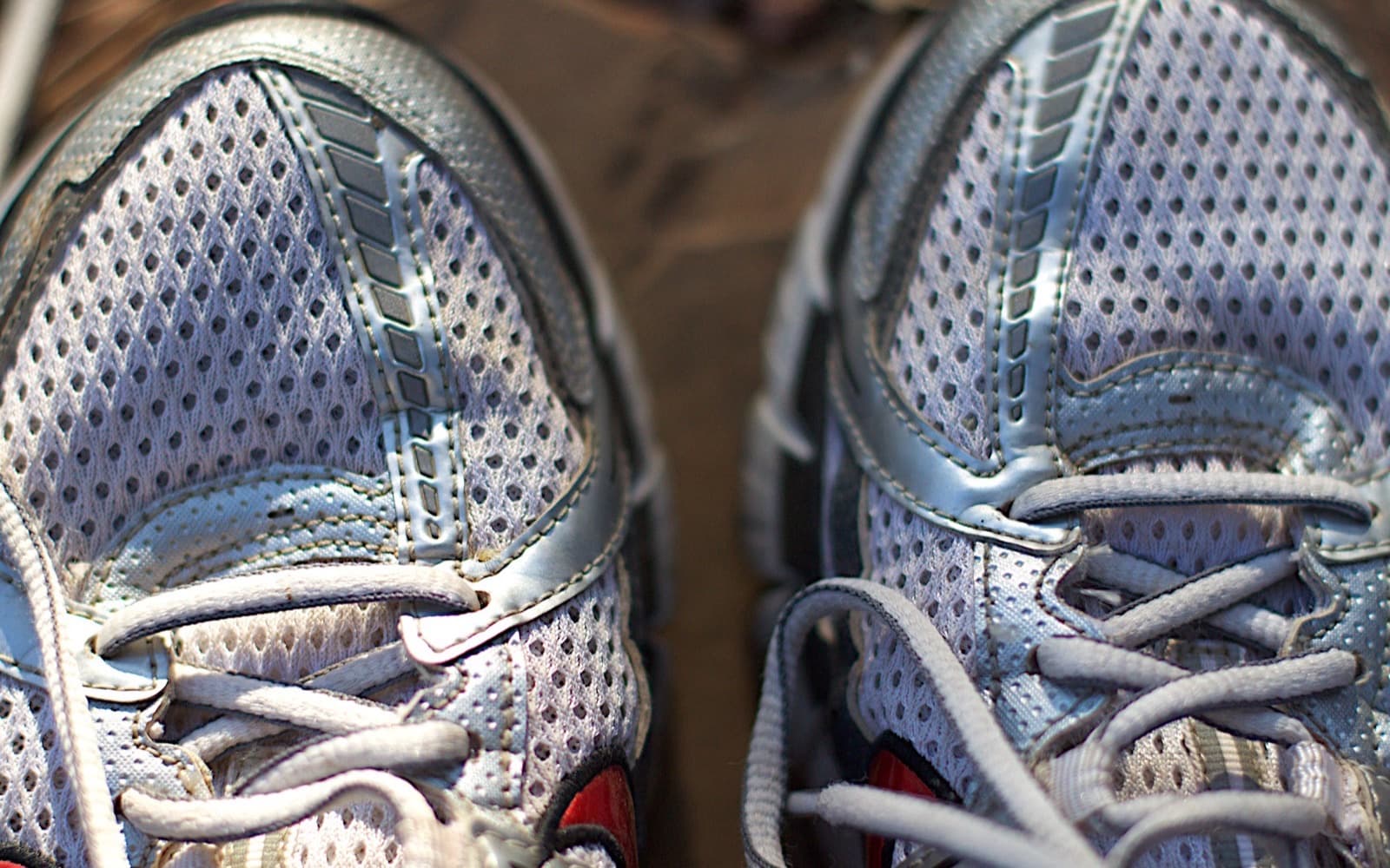 Close-up from above of a worn pair of mesh running shoes, toe boxes and loosened laces